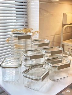 glass containers with labels on them are sitting on a white table next to a window