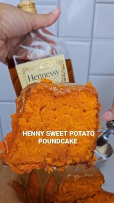 a person holding up a piece of cake in front of a bottle of henny sweet potato poundcake