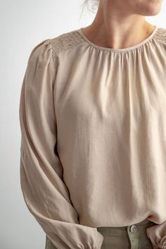 Introducing the Cove blouse—a timeless neutral blouse designed to elevate your everyday wardrobe. This piece features lovely smocking on the shoulders, a modest neckline with back button closure, and puff sleeves gathered with elastic at the wrists. The crisp shell-colored fabric is gently textured, for a simple, yet sophisticated look, perfect for any occasion. Style: gathered neck, smocked shoulder blouse Fit: true to size, although the sleeves are flowy Color: shell Fabric content: 80%Tencel, 20% Polyester Care instructions: Machine wash cold with like colors, tumble dry low. For best results, always follow care instructions on garment label. Our sizing is always approximate and can vary due to personal preference and style. For the best experience - and to make life easier for everyone Workwear Long Sleeve Blouse With Elastic Shoulders, Feminine Tops With Smocked Bishop Sleeves, Feminine Blouse With Smocked Back For Brunch, Feminine Blouse For Brunch With Smocked Back, Solid Color Puff Sleeve Tops With Smocked Back, Solid Color Tops With Smocked Back And Puff Sleeves, Cream Blouse With Puff Blouson Sleeves, Cream Blouse With Blouson Bishop Sleeves, Cream Blouse With Blouson Puff Sleeves