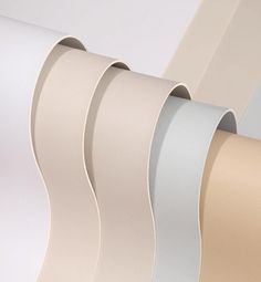 four rolls of white and beige wallpaper with different colors on each side, all lined up together