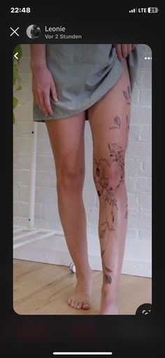 a person with tattoos on their legs standing in front of a brick wall and floor