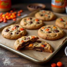 chocolate chip cookies on a cookie sheet with candy corn and orange candies in the background