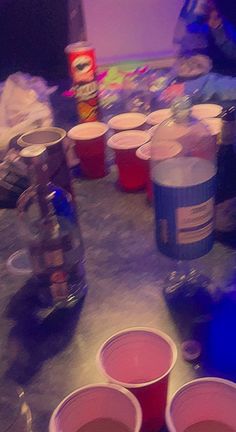 red cups sitting on top of a table next to cans of soda and other drinks