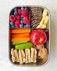 a bento box filled with fruits, vegetables and crackers on top of a table