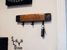 a pair of keys hanging on the wall next to a wooden key holder and sign