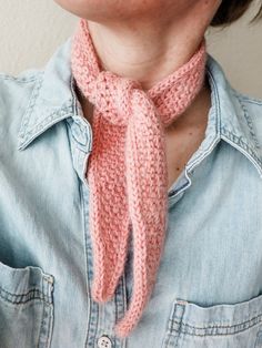 a close up of a person wearing a pink knitted neck tie and denim shirt