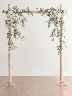 two wooden poles with flowers and greenery on them in front of a white wall