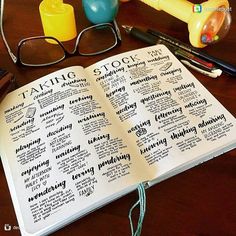 an open book sitting on top of a wooden table next to eyeglasses and pens