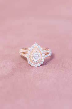 a close up of a diamond ring on a pink surface