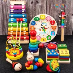 an assortment of colorful toys on top of a black table next to a wooden clock