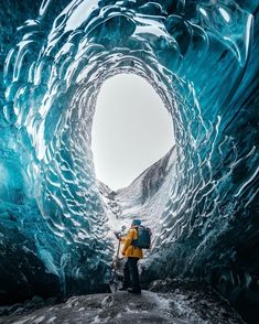 a man standing in the middle of a large ice cave