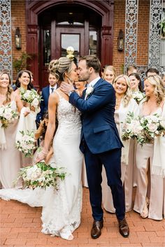 a bride and groom kissing in front of their wedding party