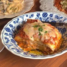 a close up of a plate of lasagna on a table with other dishes in the background