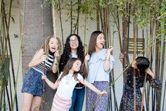 a group of women standing next to each other in front of bamboo trees with their mouths open