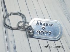 a metal keychain with the words age and gotz on it sitting on top of a wooden floor