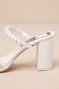 Everyone will be swooning over your look when you step out in the Dolce Vita Barrit Pearl Vanilla Embellished Strappy High Heel Sandals! Smooth faux leather shapes these stunning heels with an almond footbed and two slender toe straps, followed by a matching vamp strap, all embellished with organically-shaped faux pearls in varying sizes. The simple slide-on design makes for effortless on-and-off, while a snake-embossed block heel completes the look! 3. 25" wrapped block heel. Lightly cushioned Summer Pearl Embellished Block Heel Heels, Chic Pearl Embellished Ankle Strap Wedding Shoes, Chic Open Heel Pearls Heels, Glamorous White Sandals With Padded Heel, Elegant Embellished Sandals With Block Heel, Elegant Embellished Block Heel Sandals, Spring Pearl Embellished Block Heels, Glamorous White Sandals With Heel Strap, Elegant Pearl Embellished Round Toe Sandals