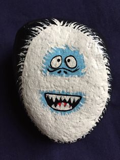 a white and blue painted rock with an evil face