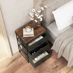 a nightstand with three drawers next to a bed and a clock on the side table