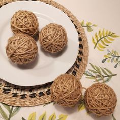 three balls of twine on a white plate next to a wicker basket with yellow flowers