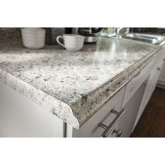 a kitchen counter top with white cabinets and drawers