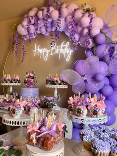 a birthday party with purple balloons, cake and cupcakes