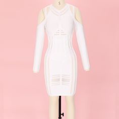 a white dress with cutouts on the shoulders and long sleeves is displayed in front of a pink background