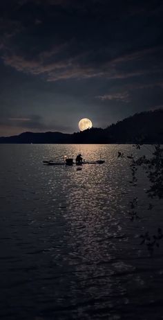 two people in a row boat on the water at night with the moon behind them