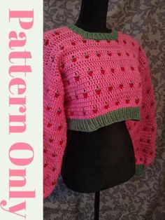 a pink sweater with green trim on top of a mannequin