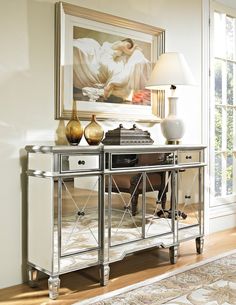 a silver and white sideboard with two lamps on it's sides in front of a painting