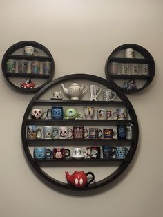 two mickey mouse head shelves with cups and mugs on them in front of a wall