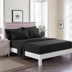 a bed with black sheets and pillows in a room