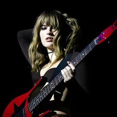 a woman holding a red guitar in her right hand