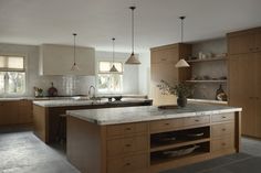 a large kitchen with wooden cabinets and marble counter tops, along with an island in the middle