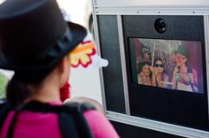 a woman wearing a black hat and pink shirt looking at pictures on a white wall