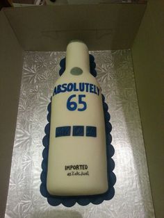 a cake shaped like a bottle with the number 65 on it is in a box