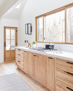 a kitchen with wooden cabinets and white counter tops, along with an area rug on the floor