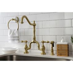 a kitchen sink with gold faucet and soap dispenser