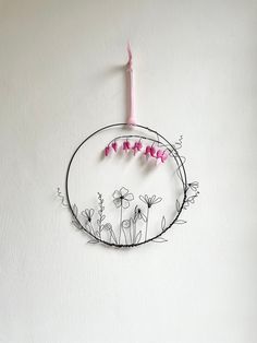 a pink candle sitting on top of a metal circle with flowers and vines around it