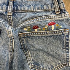 a pair of jeans with embroidered mushrooms on them