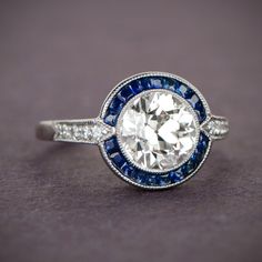 A stunning sapphire halo surrounding a beautiful old European cut diamond. Jewelry Redesign, Anniversary Diamond Ring, Estate Engagement Ring, Sapphire And Diamond Engagement Ring, Bezel Set Diamond Ring, Estate Diamond Jewelry, European Cut Diamond Ring, Vintage Sapphire Ring, Diamond Ring Wedding