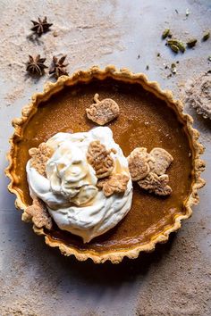 a pie with whipped cream and cookies in it on a table next to anisette