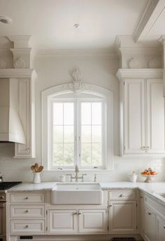 a kitchen with white cabinets and an arched window over the sink is pictured in this image