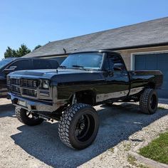 a black truck is parked in front of a house with two other trucks behind it