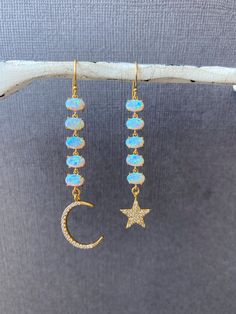 Opal Dangling Earrings, Mismatched Moon and star dangling earrings, Long gold Blue opal earrings, Bridesmaids earrings, Gift for her, jewelhavenstudio Our Opal Mismatched Moon and Star Earrings. These stunning dangling earrings feature blue opal accents, making them a perfect choice for weddings and bridesmaids. The unique design adds a touch of elegance and charm --------------------------------------------------------------------- + FEATURES + - Lab made Opal charms  - High Quality Gold plated over brass moon and star - Gold filled ear wire - Cubic Zirconia --------------------------------------------------------------------- ** HOW TO TAKE CARE OF YOUR JEWELRY ** - Remove your jewelry when swimming, sunbathing ad showering - Keep them away from chemicals like perfumes, body creams & hai Celestial Style Dangle Earrings With Star Charm, Celestial Dangle Earrings With Star Charm, 14k Gold Filled Moon Charm Dangle Earrings, Celestial Dangle Earrings For Wedding, 14k Gold Filled Dangle Earrings With Moon Charm, 14k Gold Filled Dangle Earrings With Star Charm, Celestial Style Drop Earrings With Dangling Charms, Blue Opal Earrings, Bridesmaids Earrings