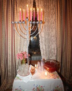 a menorah with lit candles on a table in front of a curtained window