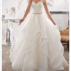 a woman in a white wedding dress posing for the camera with her hands on her hips