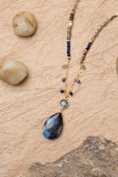 Discover the vibrant and stunning colors of the Blue Moon Collection in this eclectic necklace! Gold Filled (Lead & Nickel Free) Lapis Lazuli, Pyrite, Sodalite, Labradorite, Mother Of Pearl, Abalone 30.5-32.5" adjustable length, with gold filled lobster claw clasp We hand select our natural materials, thus there may be slight variations in color and/or size that will not detract from the overall aesthetic. Our unique handcrafted designer jewelry for women is made in America, each design created Blue Labradorite Necklaces For Healing, Handmade Bohemian Sapphire Necklace, Fusion Style Teardrop Gemstone Necklaces, Fusion Style Teardrop Gemstone Necklace, Fusion Teardrop Gemstone Necklace, Blue Labradorite Bohemian Jewelry, Bohemian Sapphire Necklaces With Natural Stones, Bohemian Blue Labradorite Jewelry, Blue Labradorite Gemstone Bead Necklaces