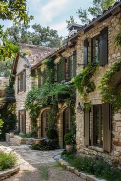 a stone house with lots of windows and plants growing on the side of it's walls