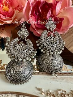 Minimalism at its finest! This is a simple, no fuss  brass-based textured silver tone finish jhumka style earrings which has a very contemporary style. The combination of plain matte silver polish look with the carvings and the pearl embellishments is just the right addition to any everyday outfit. Again, It's the right balance you need to make a statement but not over the top.   Also, very light on the ears! the craftsmanship has been perfected with these simple jhumkas.    Highlights of the piece: ** Dangled full jhumka style earrings with height: 4 inch ** Pushback in the back for the earrings ** Free shipping over $35 The measurements are approximate.  If you have any further questions, feel free to reach out to us. Care Instructions  Highlights: Protect your Jewellery from Sharp Blows Silver Pierced Pearl Earrings For Festive Occasions, Festive Silver Pearl Pierced Earrings, Silver Pearl Earrings With Intricate Design For Celebrations, Silver Pearl Drop Earrings With Intricate Design, Silver Bohemian Pearl Earrings For Gifts, Bohemian Silver Pearl Earrings For Gifts, Silver Fusion Bridal Earrings With Intricate Design, Silver Bohemian Pearl Drop Earrings, Silver Dangle Pearl Earrings With Intricate Design