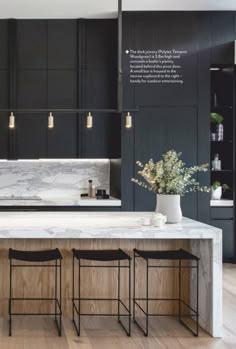 a kitchen with marble counter tops and stools in front of the island, surrounded by black cabinets